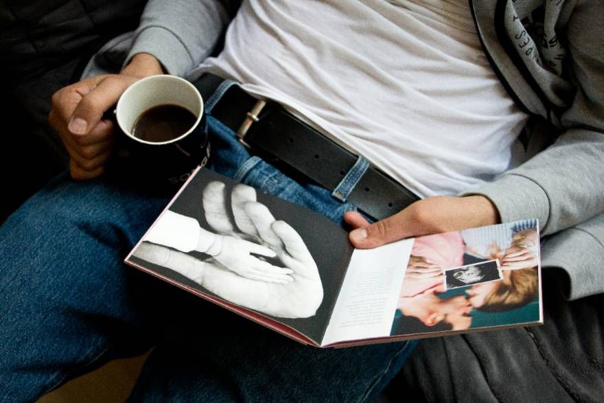 Someone holding an open printed photo book with a coffee